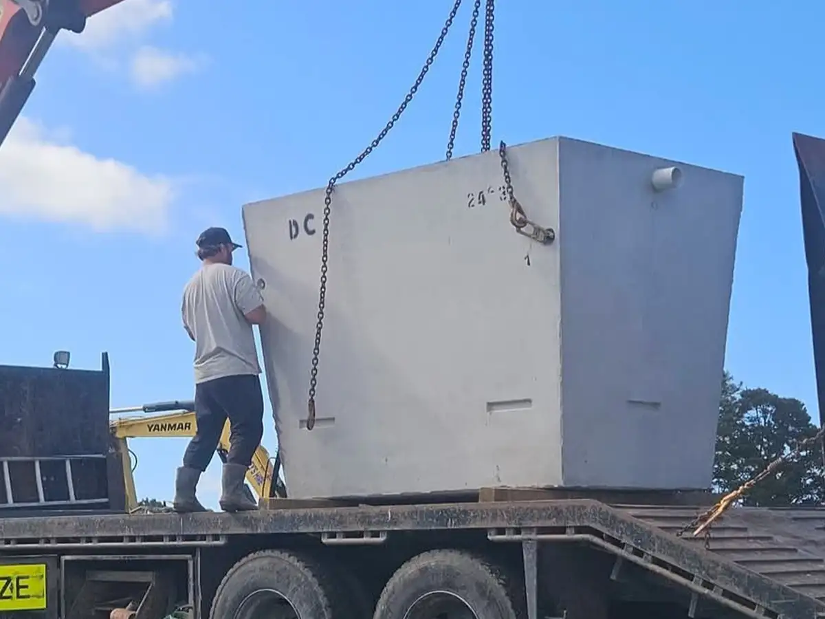 Concrete septic tank being craned off a truck for installation on a Northland property