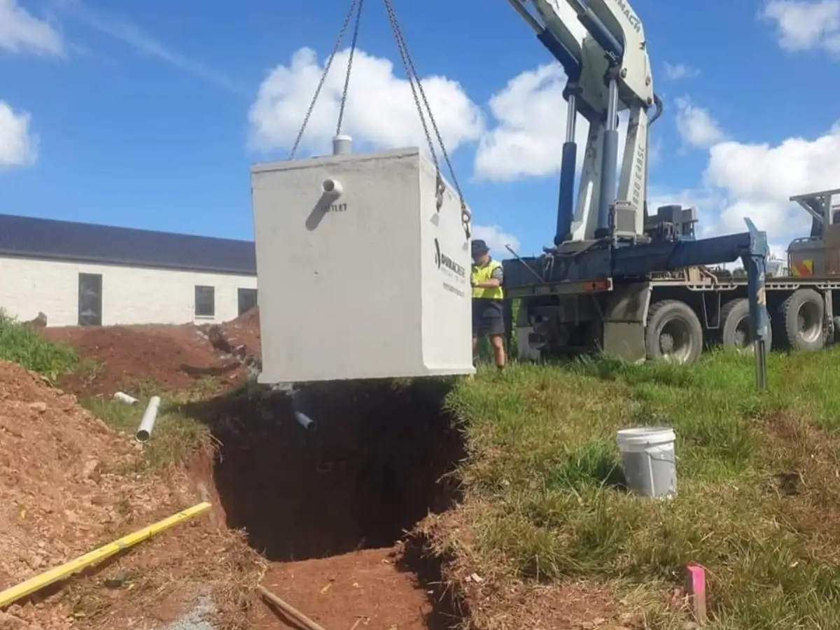 Duracrete concrete septic tank being lifted by truck crane into an excavated hole on a Northland property