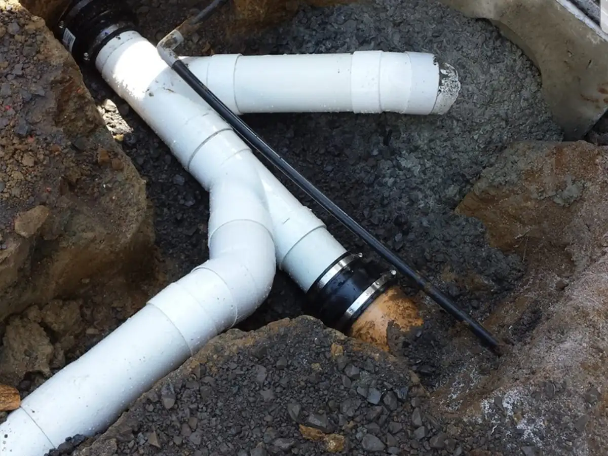 New PVC drain junction joined to an old earthenware pipe with a rubber coupling during a residential drain repair in Whangarei